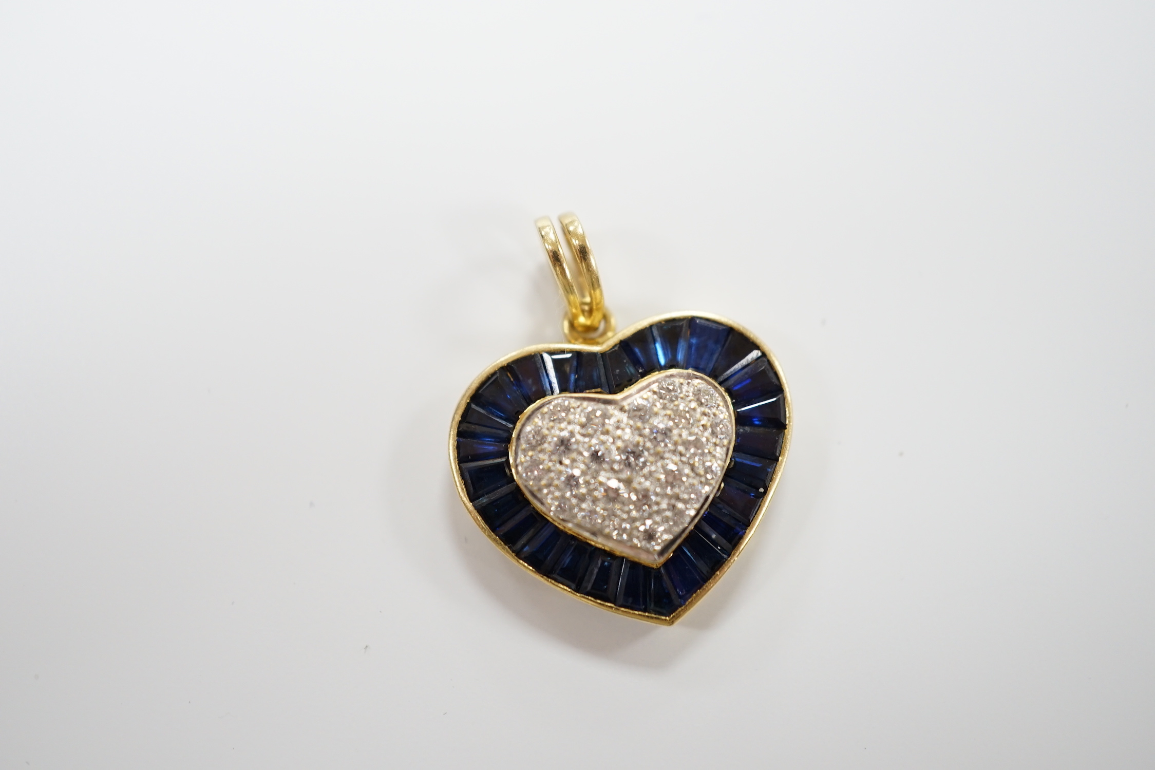 A modern 18k, pave set sapphire and diamond heart shaped pendant, overall 25mm, gross weight 4.9 grams.